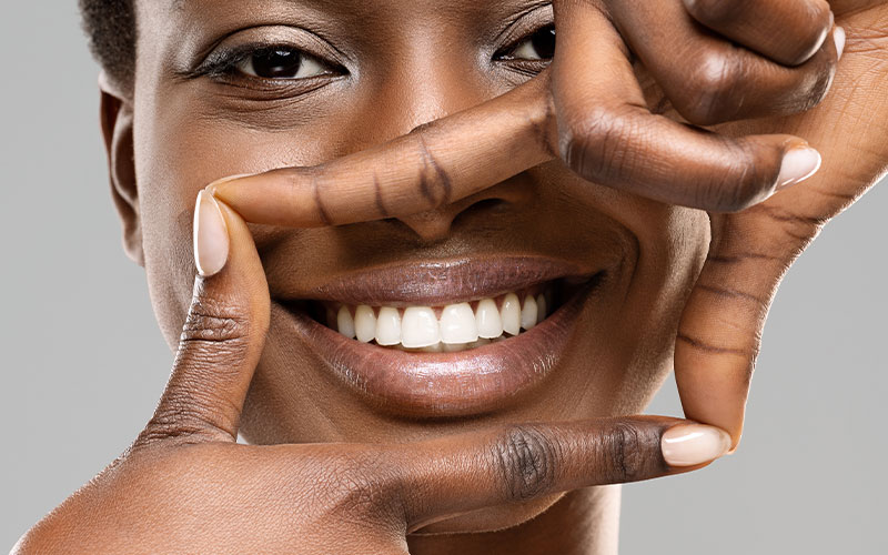 The image features a person making a peace sign gesture with their fingers, smiling broadly at the camera.