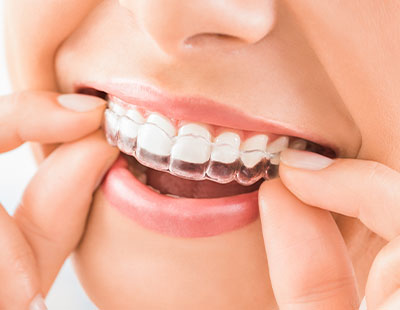 A close-up of a person s smiling mouth, showing white teeth and dental braces adjustment.