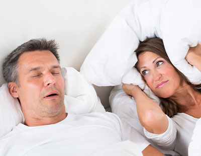 A man and woman in bed, both wearing headphones and appearing to be asleep.